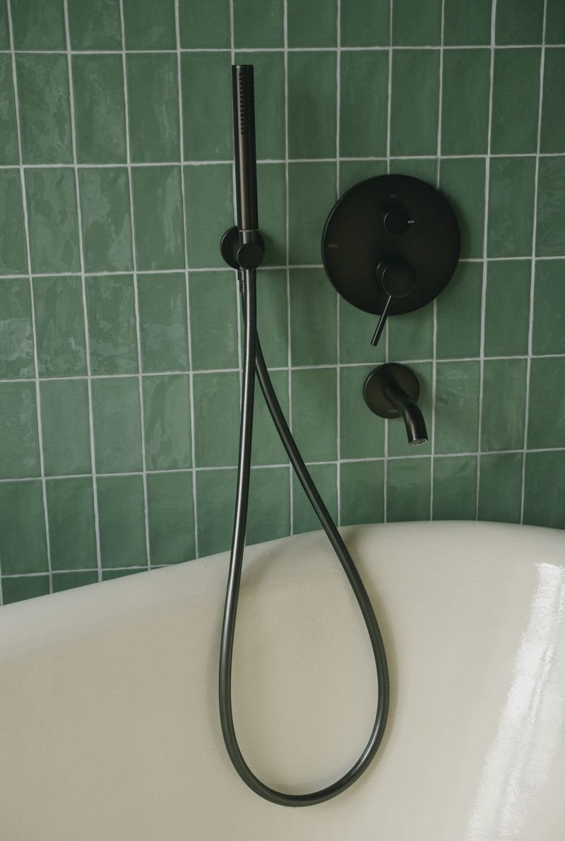 A finished tub and shower set against green tile, representative of remodel work
