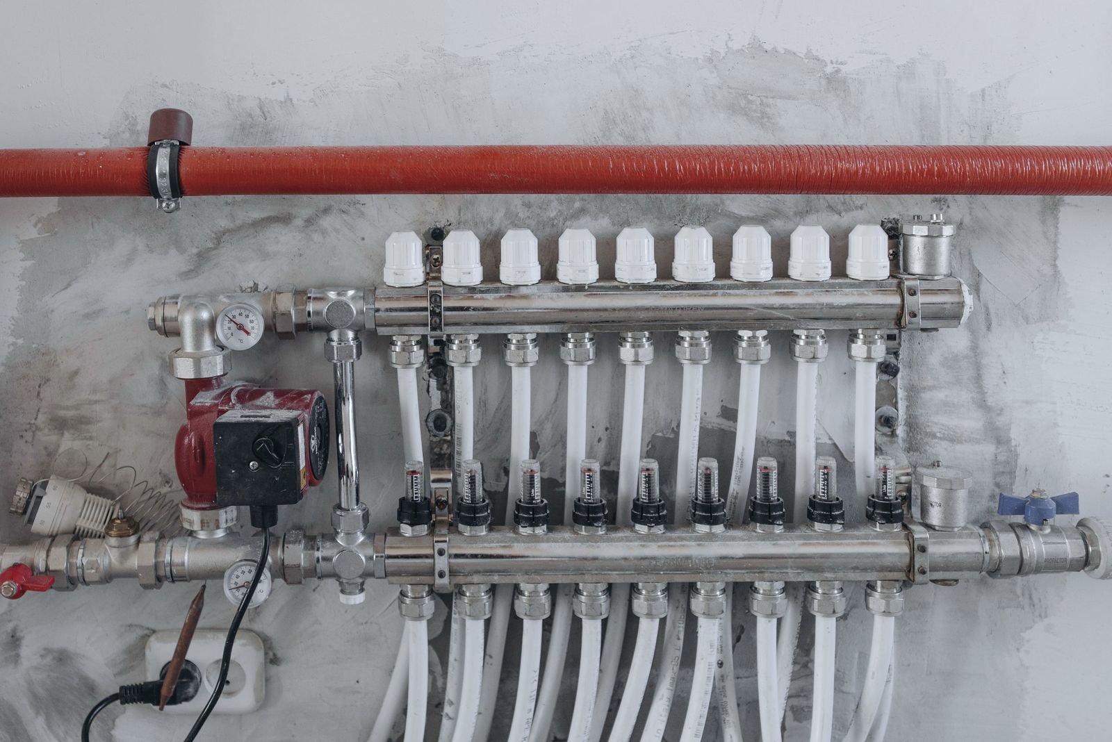 A radiant heating manifold with supply loops on a rough wall, representative of the trade