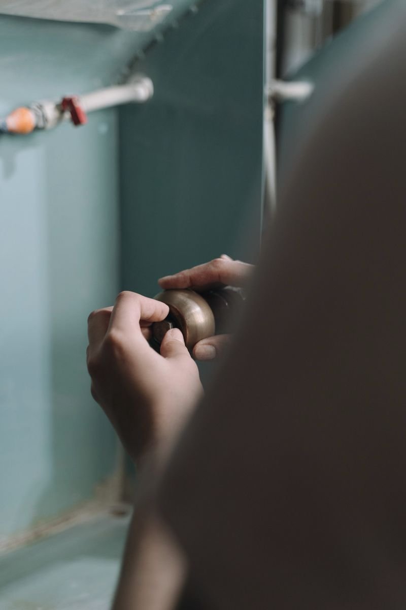 A plumber's hands fitting a valve on a wall-mounted supply line, representative of the trade